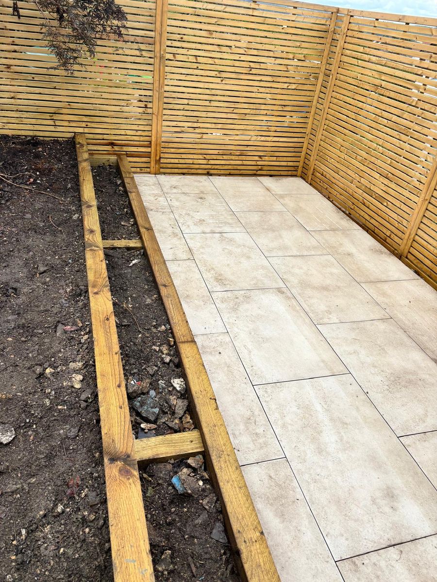 New slatted fence panels around a porcelain patio and raised bed
