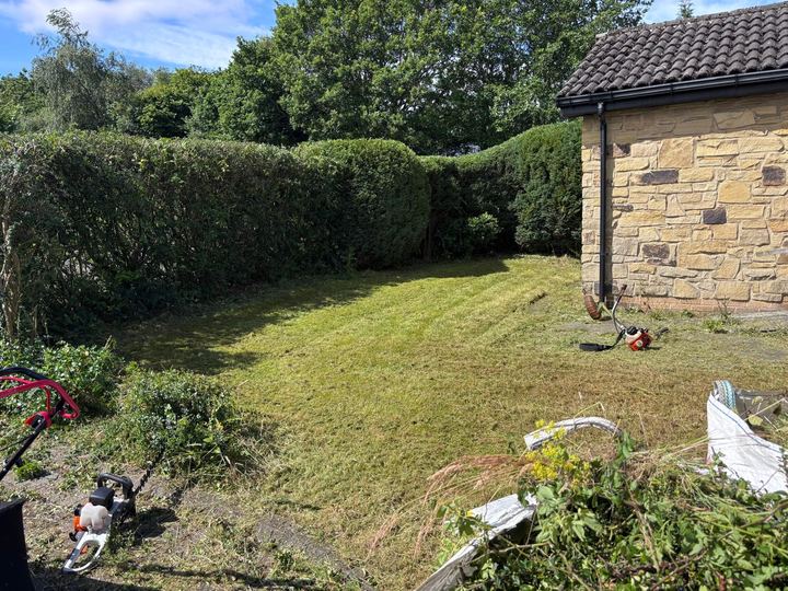 Grass cut and hedges trimmed beside a stone house