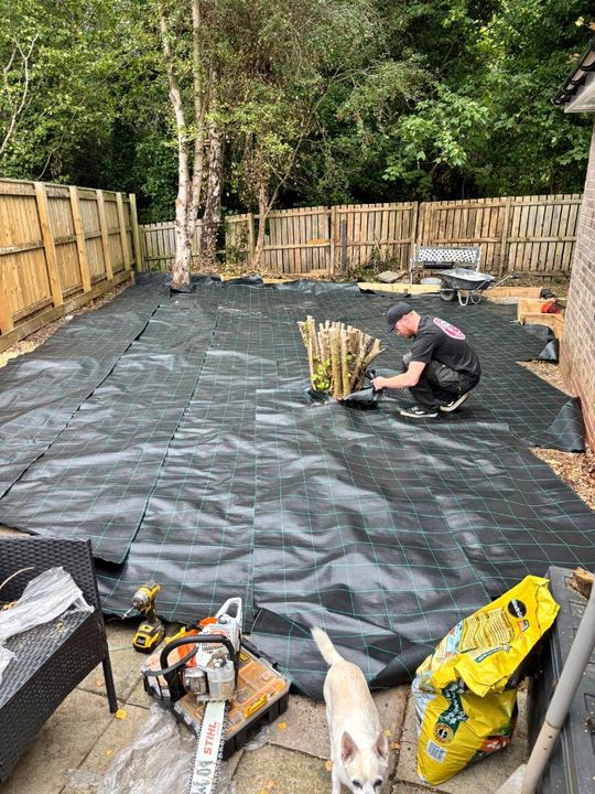 Weed membrane being laid across a garden before gravelling